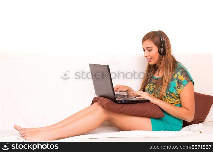 Beautiful teenager relaxing on the couch with the company of a last generation computer