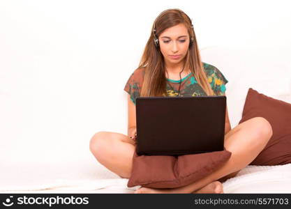 Beautiful teenager relaxing on the couch with the company of a last generation computer