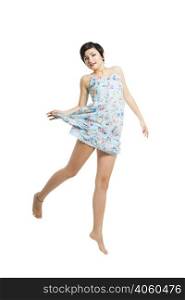 Beautiful teenager with a blue dress dancing and jumping, isolated over white background