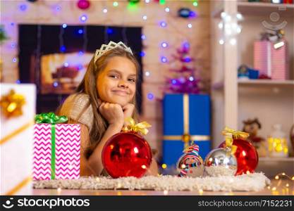 Beautiful ten-year-old girl lies on a rug in the New Year&rsquo;s interior and looks at the frame cheerfully
