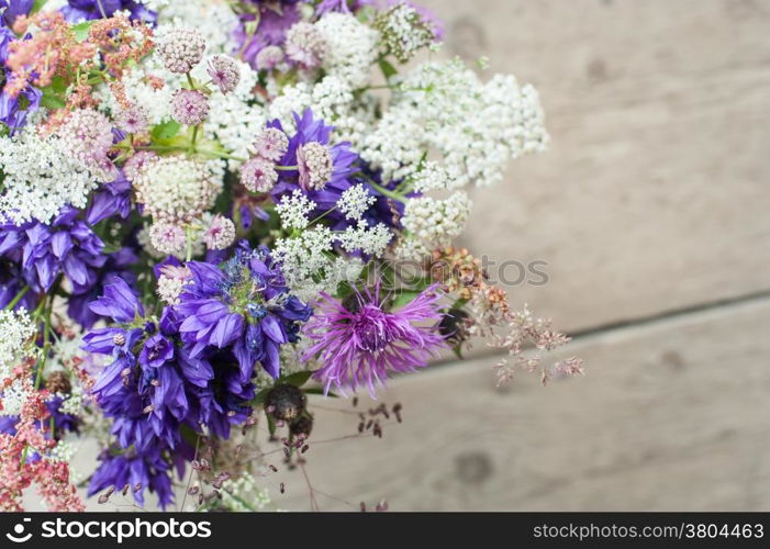 Beautiful tender bouquet of summer meadow flowers on wooden background. Floral composition in rural vintage style