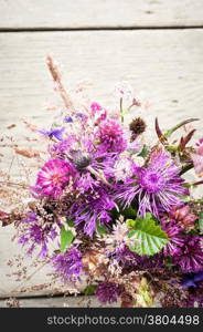 Beautiful tender bouquet of summer meadow flowers on wooden background. Floral composition in rural vintage style