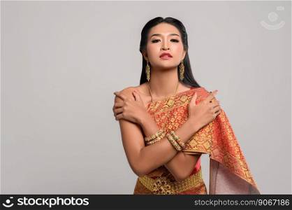 Beautiful Thai woman wearing Thai dress and standing hugging herself