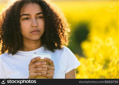 Beautiful thoughtful mixed race African American girl teenager female young woman smiling drinking takeaway coffee outside