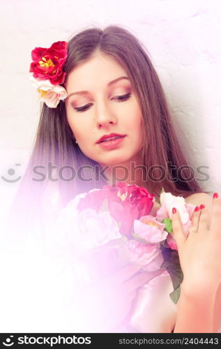 Beautiful thoughtful woman / bride in white dress looking at the bouquet of peonies