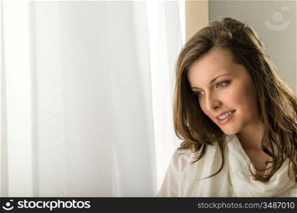 Beautiful thoughtful woman in white looking out of window