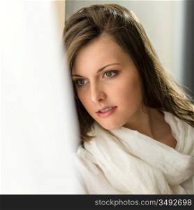 Beautiful thoughtful woman in white looking out of window