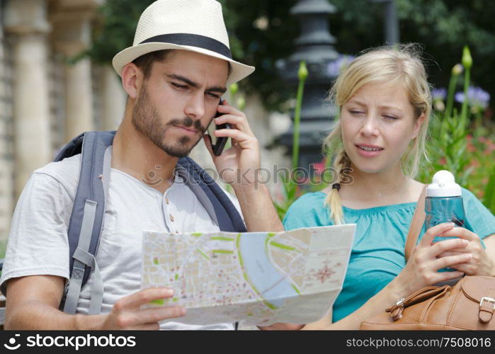 beautiful tourist couple traveling using map and phone