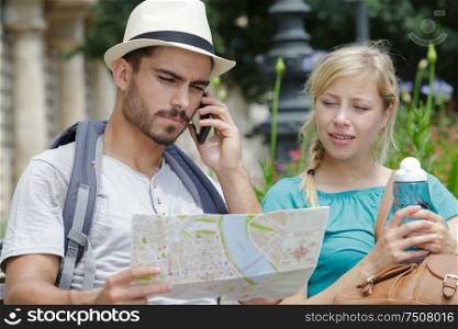 beautiful tourist couple traveling using map and phone