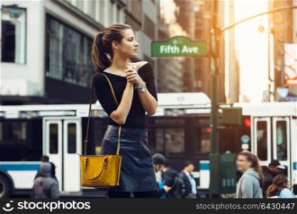 Beautiful tourist girl traveling and enjoing busy city life of New York City. Lifestyle shoot of travel blogger girl on city street.