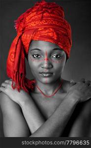 Beautiful traditional African-American woman wearing a authentic tribal red orange head scarf and red dotted makeup, heaving arms crossed on chest, isolated.