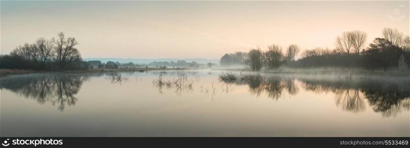 Beautiful tranquil landscape panorama of lake in mist