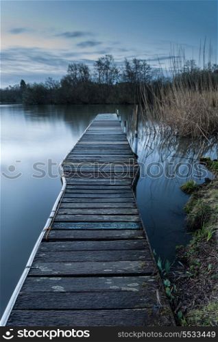 Beautiful tranquil moonlit landscape over lake and jetty