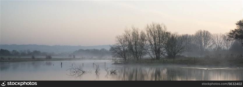 Beautiful tranquil panorama landscape of lake in mist