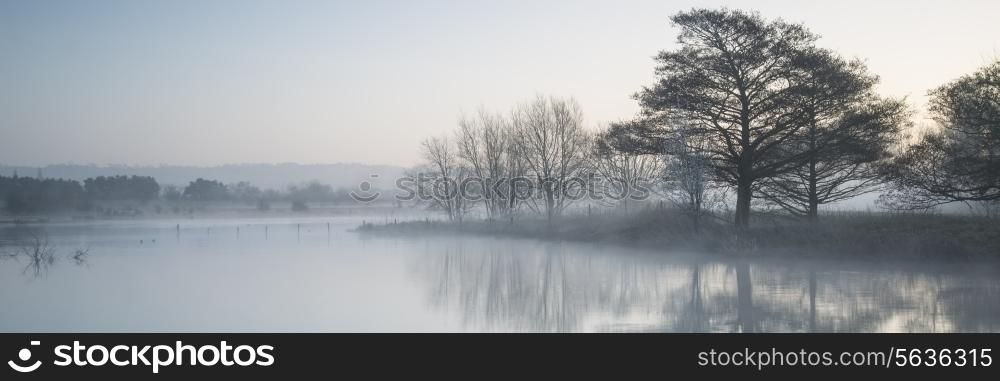 Beautiful tranquil panorama landscape of lake in mist