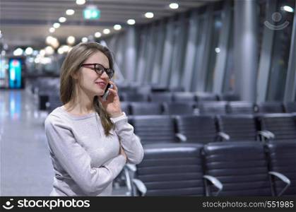 beautiful traveler with mobile phone in airport. Young, beautiful girl talking on the phone in an empty airport terminal