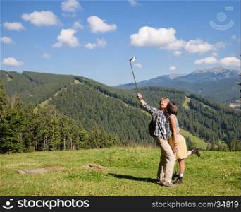 Beautiful travelling couple in love making selfie over mountain panorama
