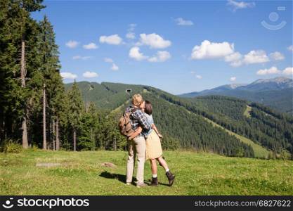 Beautiful travelling couple in love making selfie over mountain panorama