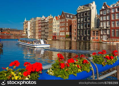 Beautiful typical Dutch dancing houses and tourist boats at the Amsterdam canal Damrak in sunny day, Holland, Netherlands.