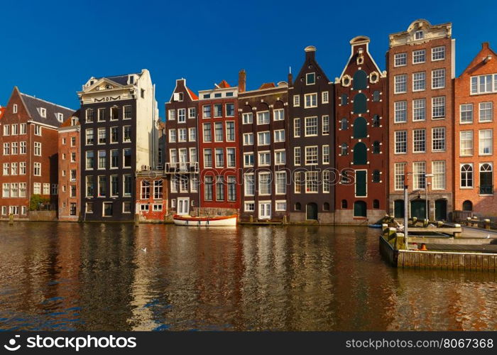Beautiful typical Dutch dancing houses at the Amsterdam canal Damrak in sunny day, Holland, Netherlands.