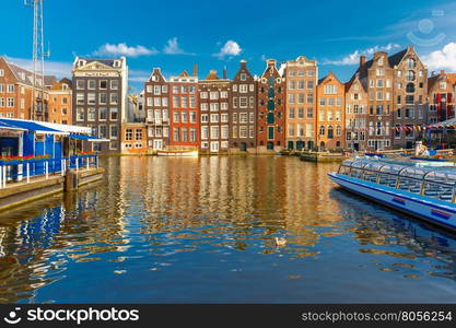 Beautiful typical Dutch dancing houses at the Amsterdam canal Damrak in the sunny evening, Holland, Netherlands.