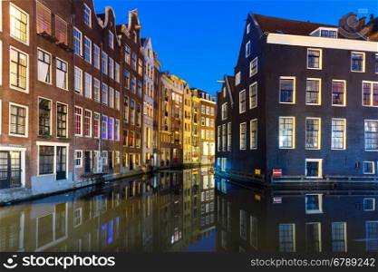 Beautiful typical Dutch houses at the Amsterdam canal at night, Holland, Netherlands.