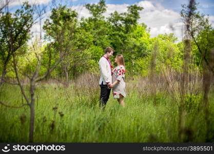 beautiful ukrainian couple holding hands at field and looking at each other
