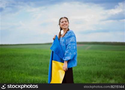 Beautiful ukrainian woman with national flag on green field background. Young lady in blue embroidery vyshyvanka. Ukraine, independence, freedom, patriot symbol, victory in war. High quality photo. Beautiful ukrainian woman with national flag on green field background. Young lady in blue embroidery vyshyvanka. Ukraine, independence, freedom, patriot symbol, victory in war.