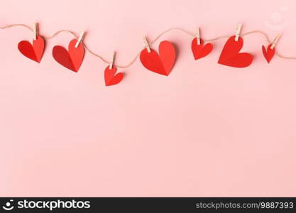 Beautiful valentines day paper hearts hanging on rope on pink background. View from above. Valentines Day Concept. 