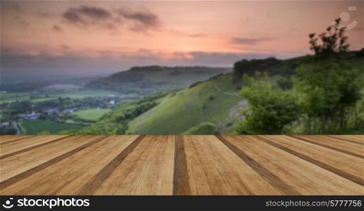 Beautiful vibrant sunrise over rolling countryside landscape with wooden planks floor