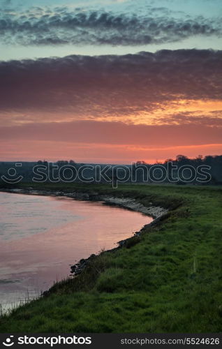 Beautiful vibrant sunrise reflected in calm river