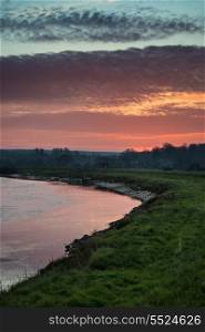 Beautiful vibrant sunrise reflected in calm river