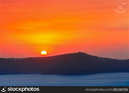 Beautiful vibrant sunset over the sea and island Thirasia, Santorini, Greece