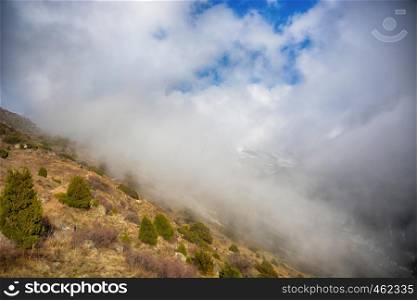 Beautiful view above the clouds over mountains and valley. Great view of the foggy Ala-Archa National Park in Kyrgyzstan.