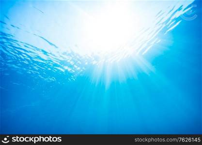 Beautiful view from underwater, sun rays through the surface of the water, underwater diving, blue water background