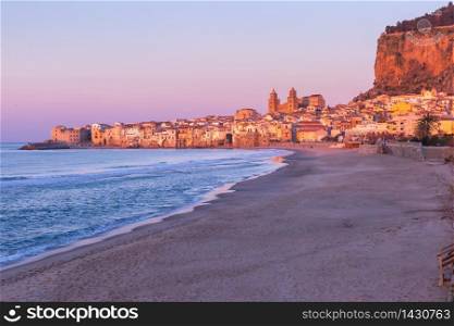 Beautiful view of empty beach, Cefalu Cathedral and old town of coastal city Cefalu at pink sunset, Sicily, Italy. Cefalu at sunset, Sicily, Italy