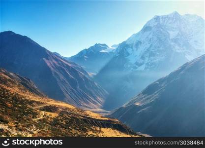 Beautiful view of mountain valley. Landscape with hills, trails and snow-covered mountain against blue sky at sunrise in Nepal. Snowy peaks of Himalayan rocks in the morning. Amazing Himalayas. Nature. Beautiful view of mountain valley. Landscape