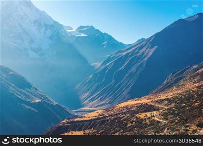 Beautiful view of mountain valley. Landscape with hills, trails and snow-covered mountain against blue sky at sunrise in Nepal. Snowy peaks of Himalayan rocks in the morning. Amazing Himalayas. Nature. Beautiful view of mountain valley. Landscape
