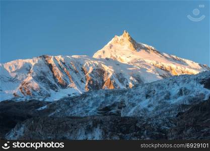Beautiful view of snow-covered mountain at colorful sunrise in Nepal. Landscape with snowy peaks of Himalayan mountains, glacier and blue sky in the morning. Amazing Manaslu. Himalayas. Nature