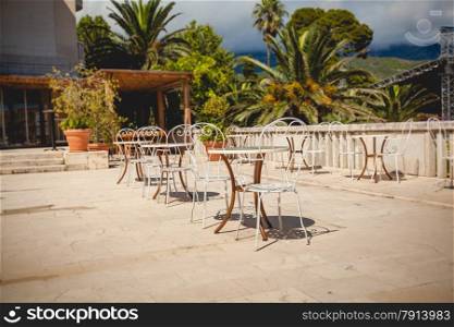 Beautiful view of summer terrace at restaurant surrounded by green palms