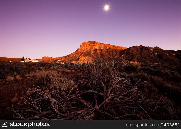 Beautiful view of the mountain ridge at sunset with full moon on the background. Teide national park on Tenerife, Canary Islands.
