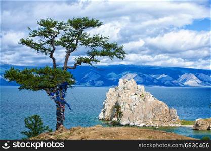Beautiful View of the Sacred Siberian stone Shamanka at Cape Burhan, Olkhon Island on the island of Baikal, Siberia, Russia with Green Larch in Cloudy Summer Day