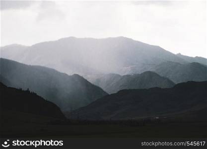 Beautiful view of the silhouettes of the Altai mountain ranges in rainy weather and fog.. Beautiful view of the silhouettes of the Altai mountain ranges in rainy weather and fog