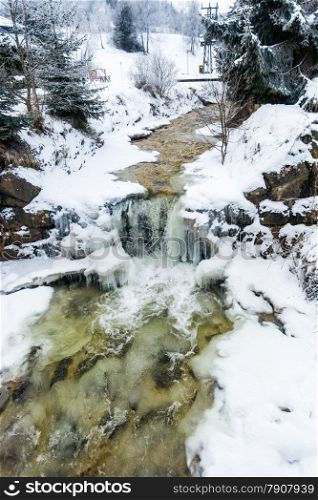 Beautiful view on small waterfall on mountain river at winter