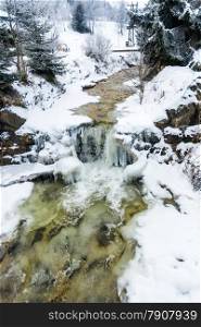 Beautiful view on small waterfall on mountain river at winter