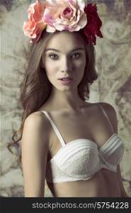 Beautiful, vintage, natural, charming woman with long curly hair, white bra, and flowers on the head.