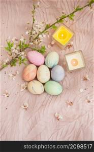 Beautiful watercolor paints on Easter eggs that lie on a delicate pink cloth along with burning candles. Easter concept. Beautiful watercolor paints on Easter eggs that lie on a delicate pink cloth along with burning candles. Easter concept.