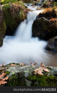 Beautiful waterfall and big rocks with moss in autumn