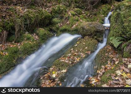 Beautiful waterfall landscape image in vibrant Autumn woodland in Lake District