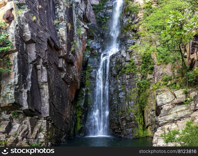 Beautiful waterfall of Veu da Noiva between the covered stones of moss and the vegetation located in an area of   completely preserved nature in the state of Minas Gerais, Brazil. Veu da Noiva waterfall  located in an area of   preserved nature